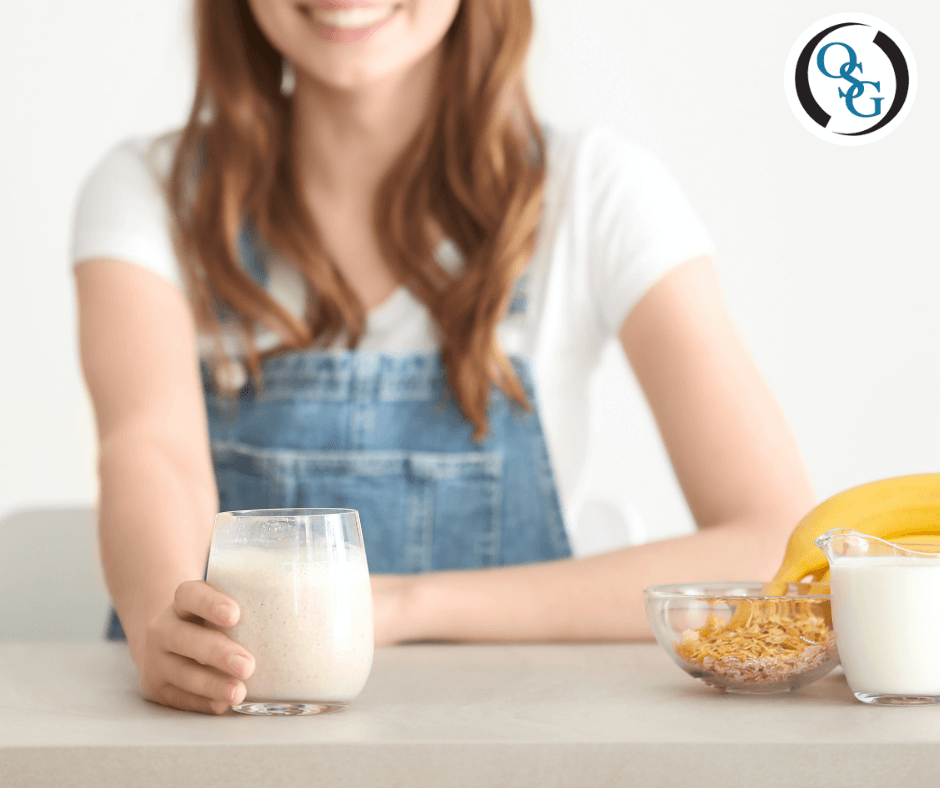 A woman holding a glass of oat milk